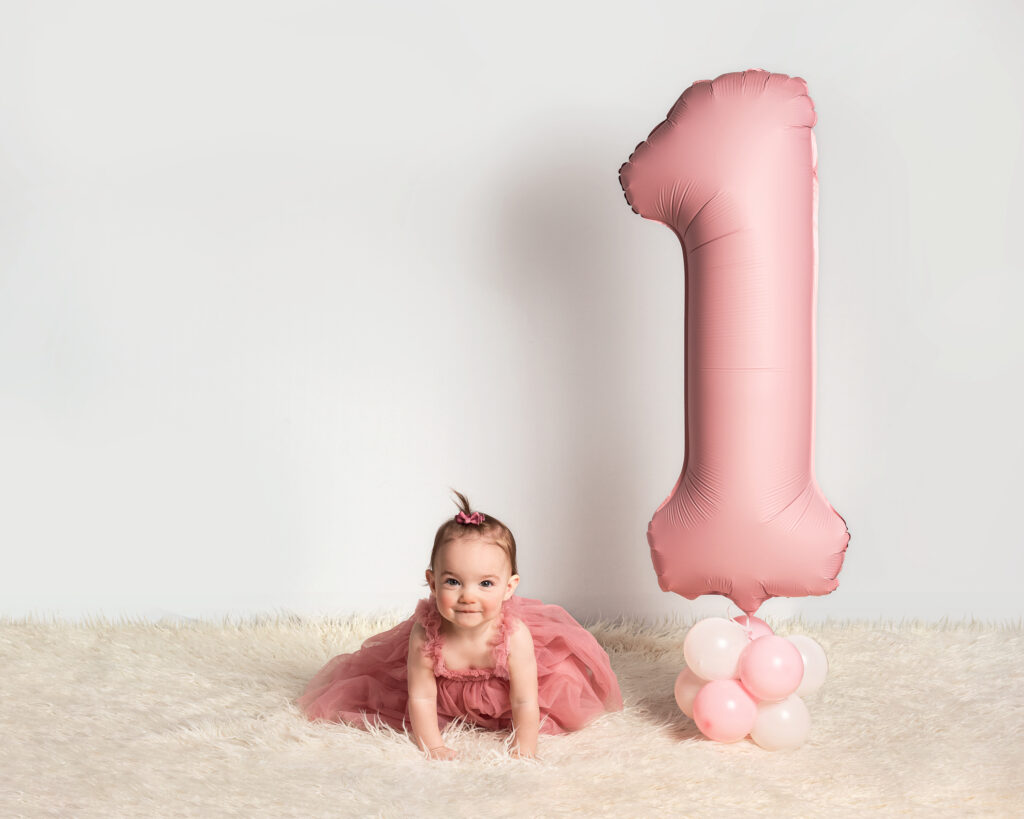 A happy baby portrait with a number one balloon
