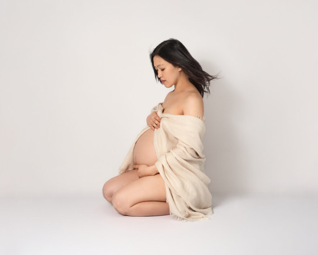 Pregnancy portrait kneeling on the floor with soft shawl