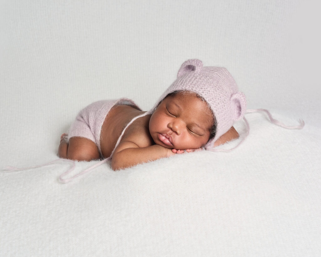 Newborn baby girl sleeping in lilac outfit during at-home photography session in Peckham, South London