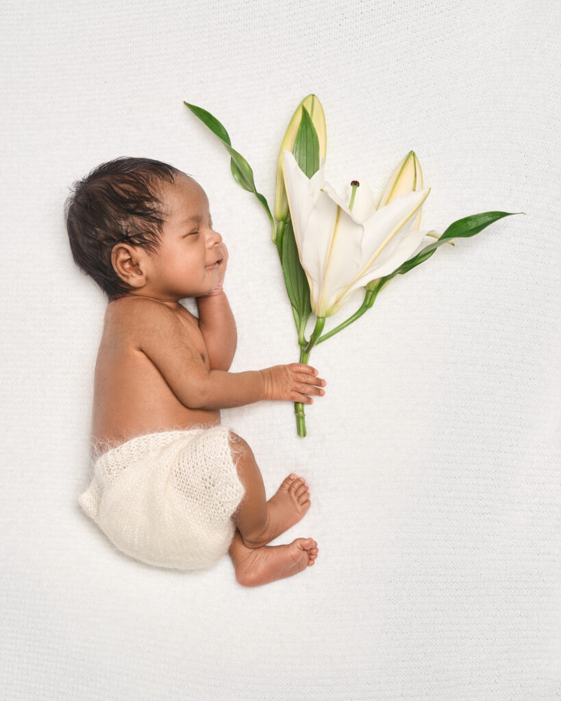 Newborn baby Lily with white lily flower – at-home newborn photography in London